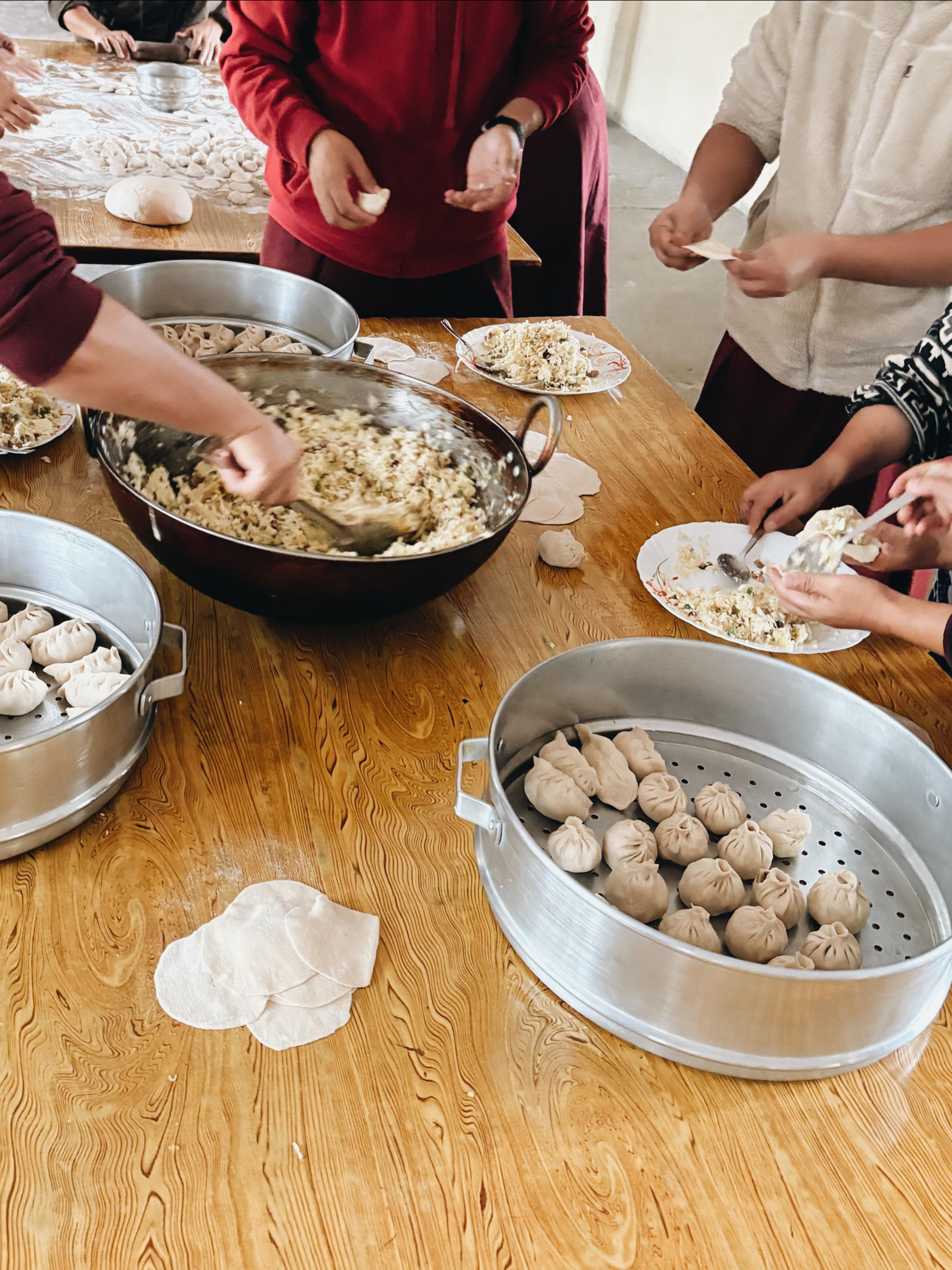 Hands shaping traditional Tibetan dumplings during the momo-making session
